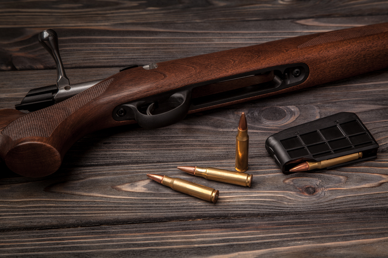 Bolt action rifle with cartridges and a detachable magazine on a wooden table