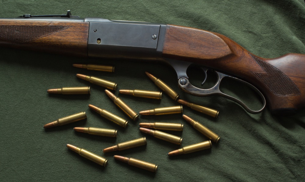 Lever action rifle with cartridges on green fabric