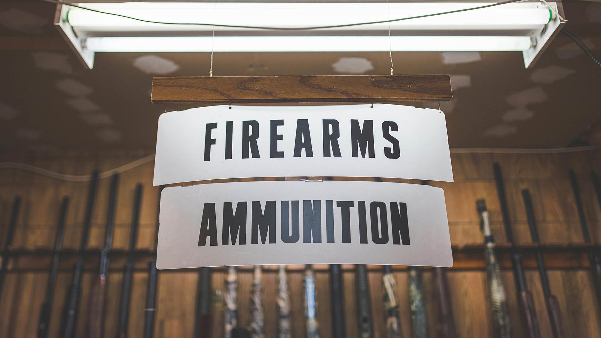 hanging signs for firearms and ammunition in front of row of rifles